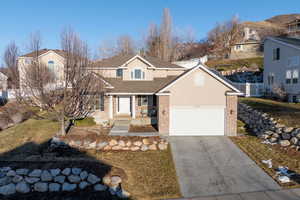 Traditional-style home featuring driveway, a front lawn, and brick siding