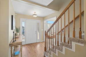 Foyer entrance featuring light wood finished floors, baseboards, and stairway