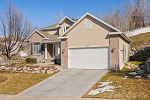 Traditional home with brick siding, stucco siding, concrete driveway, an attached garage, and fence