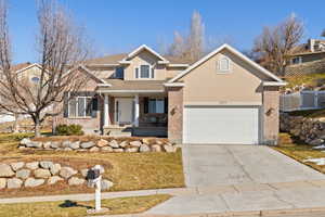 Traditional home with a garage, brick siding, fence, driveway, and stucco siding