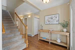 Foyer entrance featuring stairway, wood finished floors, visible vents, and baseboards