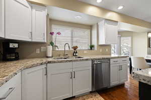 Kitchen with dishwasher, dark wood-type flooring, white cabinetry, a sink, and recessed lighting