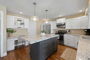 Kitchen with stainless steel appliances, built in desk, and white cabinets