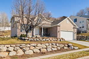 View of front of property featuring a porch, an attached garage, brick siding, concrete driveway, and stucco siding