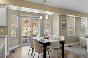 Dining room with a chandelier, light wood-style flooring, visible vents, and baseboards