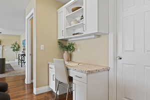 Office area with dark wood-style floors, a fireplace, built in study area, and baseboards