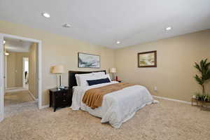 Bedroom with light carpet, baseboards, a textured ceiling, and recessed lighting