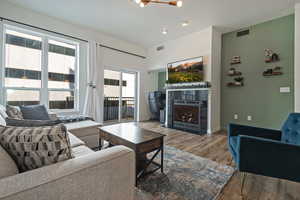 Living area with visible vents, a lit fireplace, baseboards, and wood finished floors