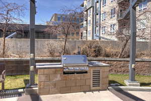 View of patio with an outdoor kitchen, grilling area, and fence