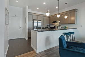 Kitchen with a peninsula, dark countertops, stainless steel fridge, and recessed lighting