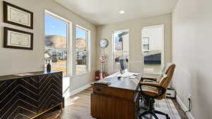 Office area featuring visible vents, baseboards, wood finished floors, a baseboard heating unit, and recessed lighting