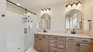 Full bath featuring double vanity, a shower stall, and a sink