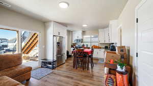 Kitchen featuring light wood finished floors, visible vents, open floor plan, stainless steel appliances, and white cabinetry