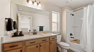 Bathroom featuring shower / bath combination with curtain, visible vents, vanity, and toilet