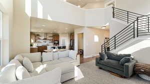 Living area with recessed lighting, a high ceiling, baseboards, stairs, and light wood finished floors