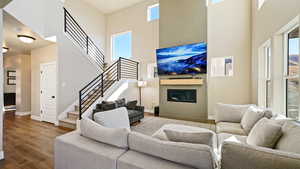 Living room featuring a glass covered fireplace, a healthy amount of sunlight, baseboards, and wood finished floors