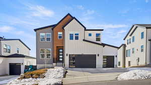 View of front of property with board and batten siding, a garage, and concrete driveway