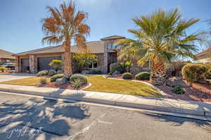 View of front of property with a garage, driveway, stone siding, stucco siding, and a front yard