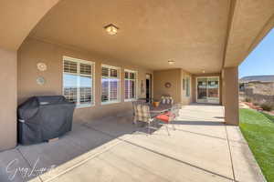 View of patio with outdoor dining space, a grill, and fence