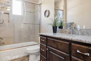 Full bathroom featuring bath / shower combo with glass door, vanity, and toilet