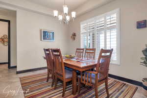 Dining room with light tile patterned floors, an inviting chandelier, and baseboards