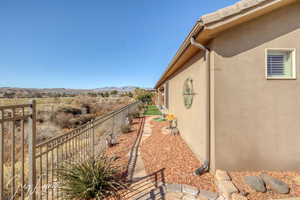 View of side of home featuring a mountain view, fence, and stucco siding