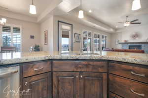 Kitchen with a fireplace, visible vents, open floor plan, a sink, and dark brown cabinets