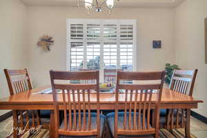 Dining room featuring light tile patterned flooring, a notable chandelier, and baseboards