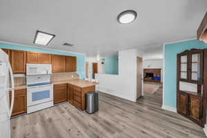 Kitchen featuring brown cabinets, white appliances, visible vents, and a peninsula