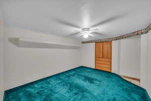 Bonus room with dark carpet, ceiling fan, and a textured ceiling