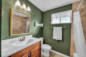 Bathroom with a bathtub, curtained shower, a textured wall, toilet, and vanity