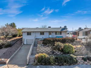 Ranch-style house featuring an attached garage, stairs, and concrete driveway