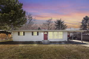 Ranch-style house with entry steps, a front yard, an attached carport, and brick siding