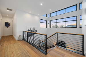 Hallway featuring recessed lighting, visible vents, hardwood / wood-style floors, an upstairs landing, and baseboards