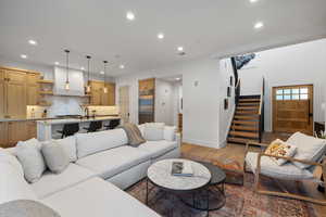 Living area with light wood-type flooring, stairway, baseboards, and recessed lighting