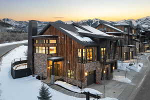 View of front of home featuring a garage, stone siding, a chimney, and a mountain view