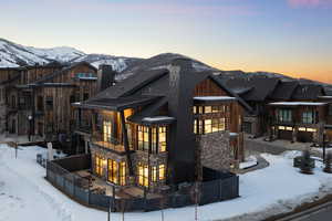 Snow covered property featuring stone siding, fence, and a balcony