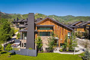 Back of house featuring a lawn, a chimney, and a mountain view