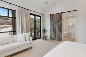 Bedroom featuring a barn door, visible vents, connected bathroom, lofted ceiling, and access to exterior