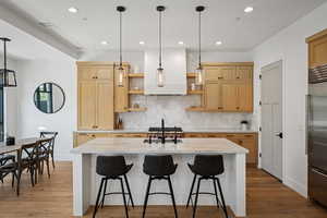 Kitchen with open shelves, high quality fridge, light wood-type flooring, decorative backsplash, and recessed lighting