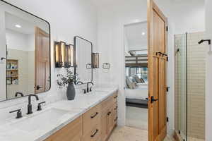 Full bathroom with double vanity, a sink, a shower stall, and ensuite bathroom