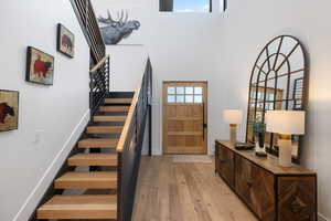 Entryway with light wood-style flooring, a high ceiling, stairway, and baseboards