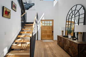 Entrance foyer featuring a high ceiling, hardwood / wood-style floors, and stairs