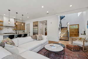 Living area featuring light wood-style flooring, stairway, and recessed lighting