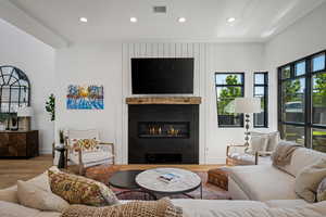 Living room with wood finished floors, a fireplace, and recessed lighting