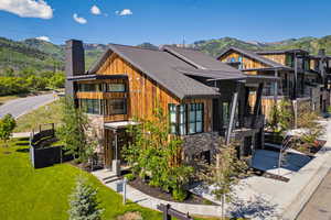 Modern home with a mountain view, a balcony, a chimney, and a front lawn