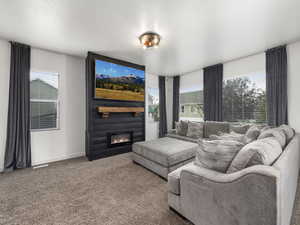 Living area with carpet floors, a large fireplace, and baseboards