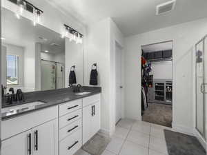 Bathroom featuring tile patterned flooring, visible vents, a sink, and a shower stall