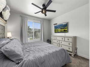 Carpeted bedroom with baseboards and a ceiling fan