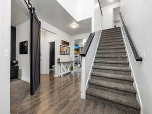 Stairway featuring a barn door, wood finished floors, and baseboards